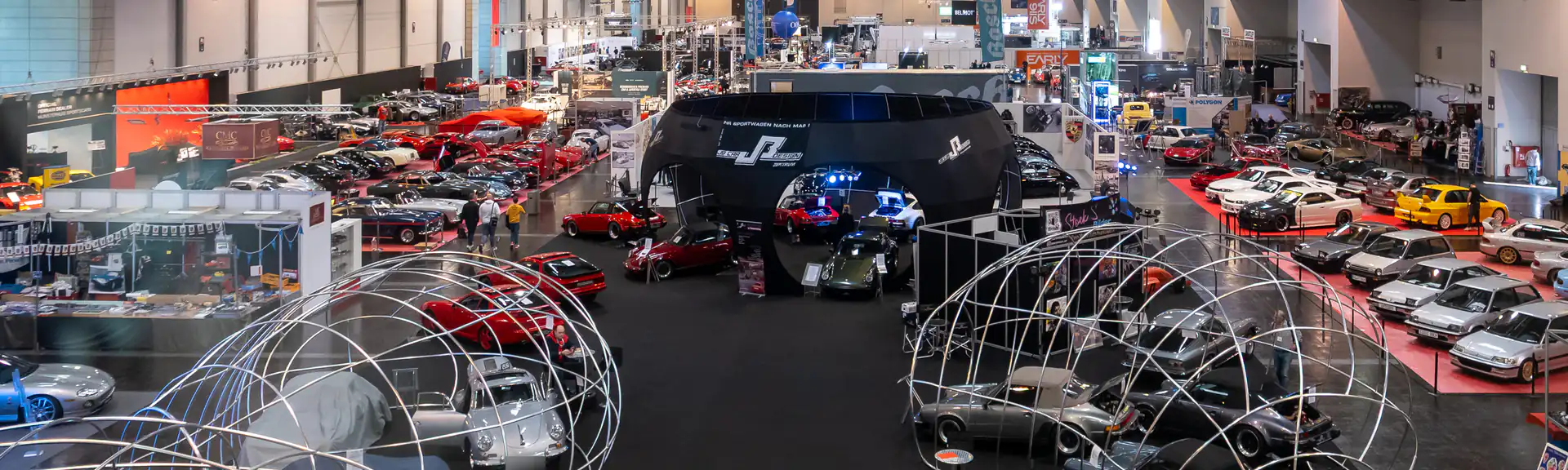 Hala 3 targów Techno-Classica w Essen z galerii – rzędy klasyków na stoiskach handlarzy, w środku czarny pawilon z Porsche 911, po prawej Hondy Civic na czerwonym podeście