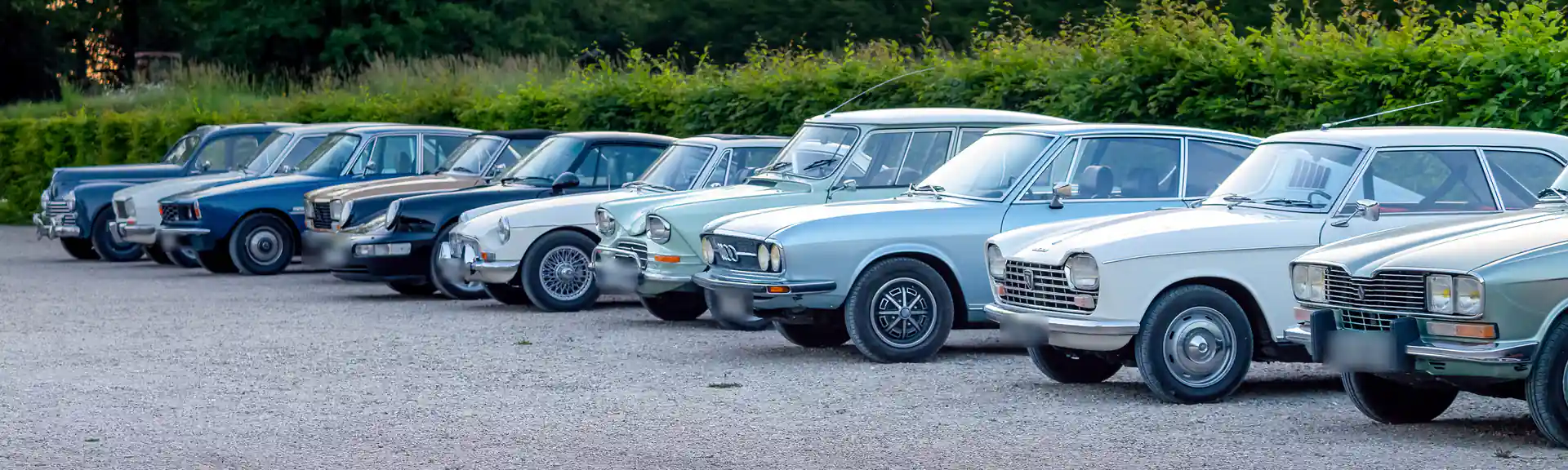 Rząd europejskich klasyków z lat 60. i 70. na żwirowym placu – od prawej Renault 16, Peugeot 204 i Audi 100 Coupé S