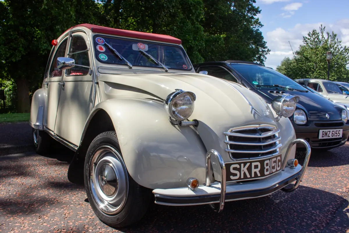 Kremowy Citroën 2CV z 1968 roku z bordowym dachem na zlocie klasyków — ujęcie trzy czwarte z przodu.