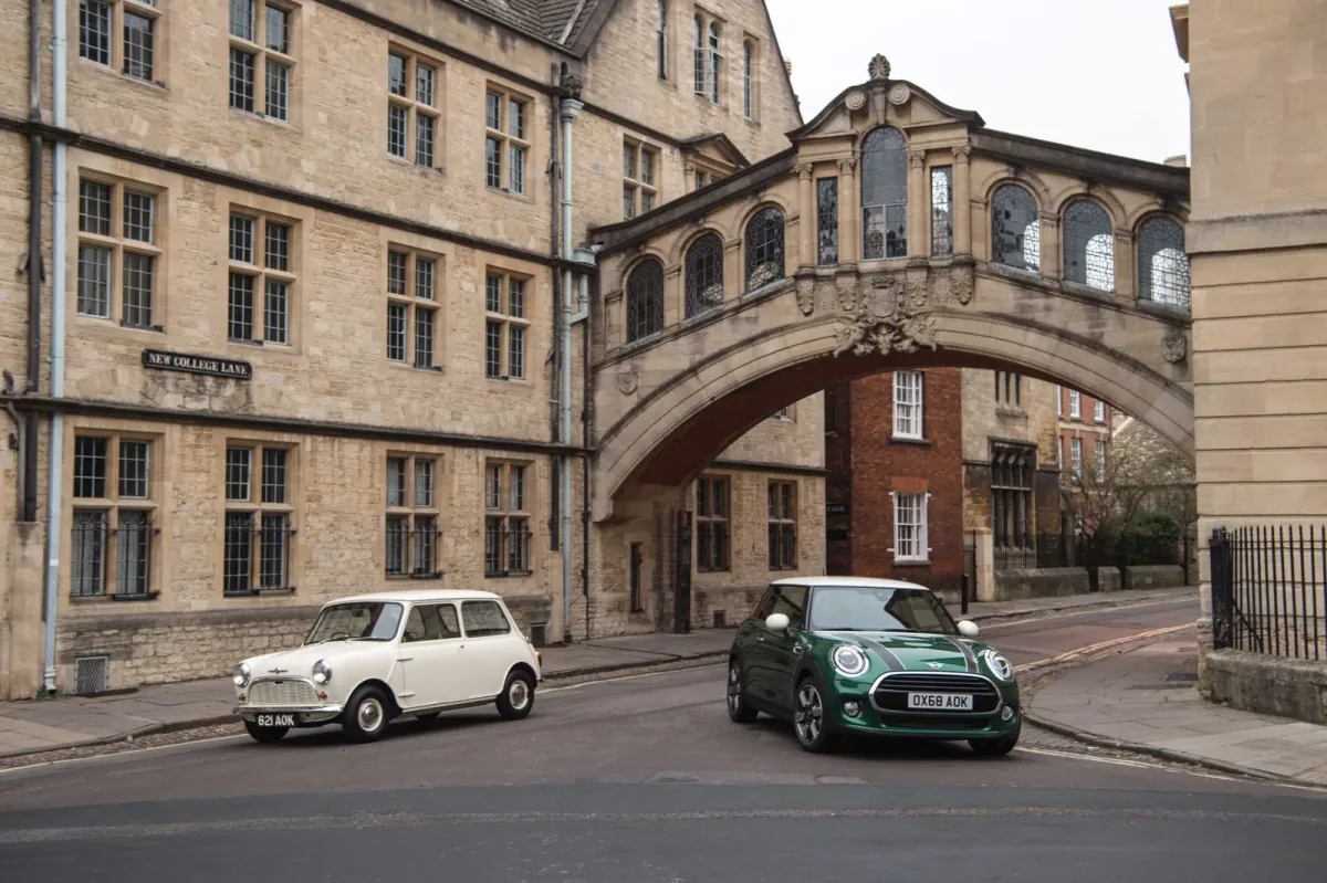 Klasyczny biały Morris Mini-Minor z 1959 roku obok zielonego MINI 60 Years Edition pod mostem na New College Lane w Oksfordzie.