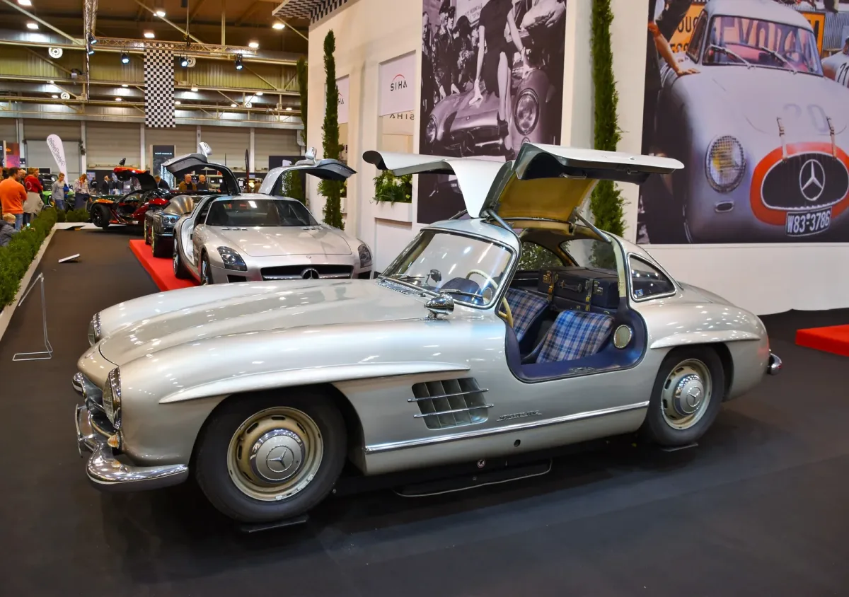 Kadru nie da się pomylić z żadnym innym autem — 300 SL Coupé ze wzniesionymi skrzydłami i kraciastą tapicerką. Drzwi w dachu nie były fanaberią stylisty: wymusiła je wysoka rama przestrzenna, przez którą inaczej nie dało się wsiąść.