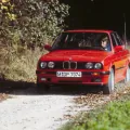 Czerwone E30 na szutrowej drodze, w materiałach prasowych BMW. Egzemplarz w takim stanie trafia dziś do ogłoszeń rzadko, a jego cena zaczyna się tam, gdzie inne się kończą.