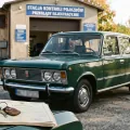Zielony Fiat 125p przed stacją kontroli pojazdów — na błotniku karta pojazdu i kluczyki. Rachunek za żółte tablice zaczyna się jeszcze przed badaniem.