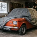 Fiat 126p pod pokrowcem w domowym garażu, za oknem śnieg. Sezon skończony — a OC wciąż tyka, chyba że wybrałeś polisę krótkoterminową.