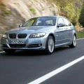 Srebrne BMW E90 na krętej drodze, widok z przodu pod kątem.