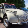 Kremowy Citroën 2CV z 1968 roku z bordowym dachem na zlocie klasyków — ujęcie trzy czwarte z przodu.