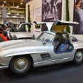 Kadru nie da się pomylić z żadnym innym autem — 300 SL Coupé ze wzniesionymi skrzydłami i kraciastą tapicerką. Drzwi w dachu nie były fanaberią stylisty: wymusiła je wysoka rama przestrzenna, przez którą inaczej nie dało się wsiąść.
