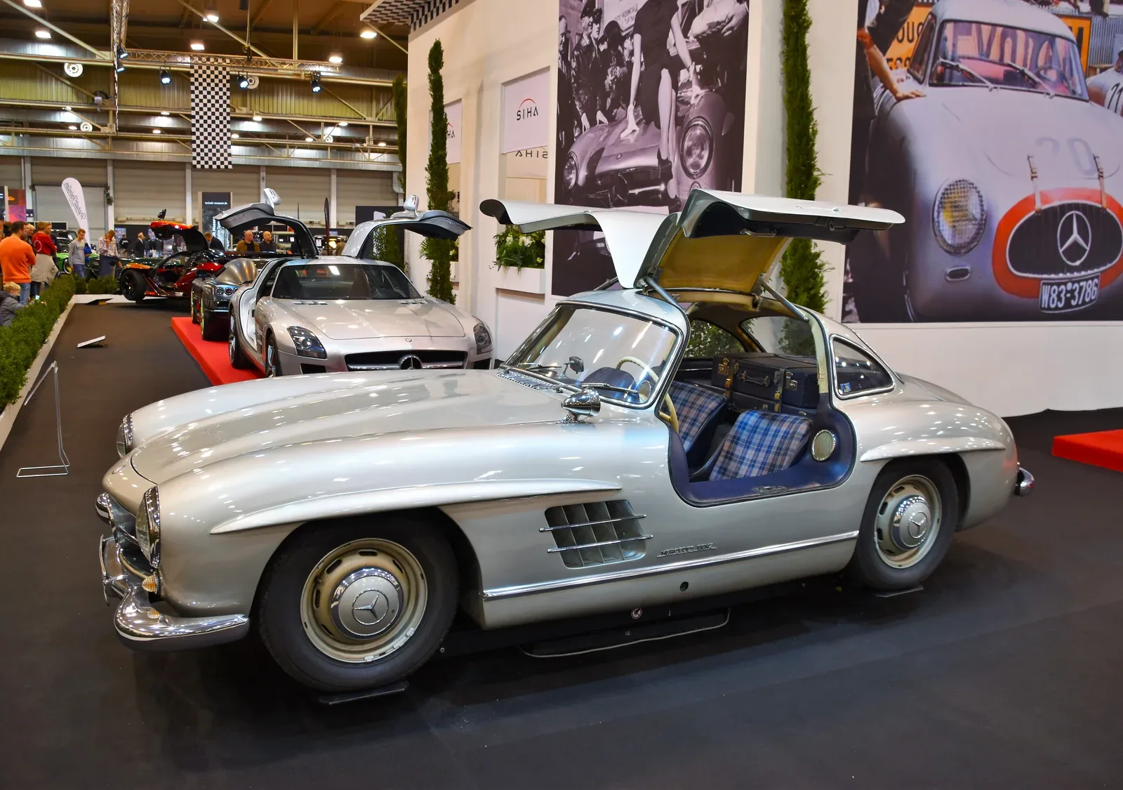 Kadru nie da się pomylić z żadnym innym autem — 300 SL Coupé ze wzniesionymi skrzydłami i kraciastą tapicerką. Drzwi w dachu nie były fanaberią stylisty: wymusiła je wysoka rama przestrzenna, przez którą inaczej nie dało się wsiąść.