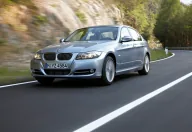 Srebrne BMW E90 na krętej drodze, widok z przodu pod kątem.