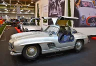 Kadru nie da się pomylić z żadnym innym autem — 300 SL Coupé ze wzniesionymi skrzydłami i kraciastą tapicerką. Drzwi w dachu nie były fanaberią stylisty: wymusiła je wysoka rama przestrzenna, przez którą inaczej nie dało się wsiąść.