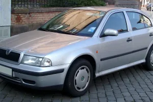 Srebrny liftback przy ceglanym murze — pojedyncze reflektory i chromowana atrapa zdradzają wersję sprzed liftingu 2000 roku, najprostszą twarz pierwszej Octavii. Samochód bez pretensji, budowany po to, żeby jeździć, a nie robić wrażenie.