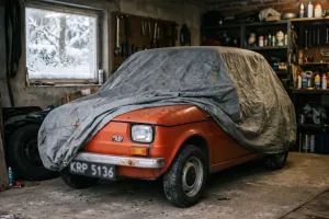 Fiat 126p pod pokrowcem w domowym garażu, za oknem śnieg. Sezon skończony — a OC wciąż tyka, chyba że wybrałeś polisę krótkoterminową.
