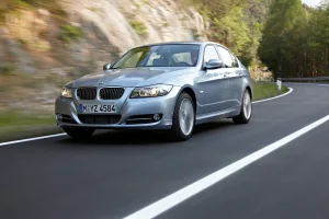 Srebrne BMW E90 na krętej drodze, widok z przodu pod kątem.