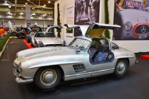 Kadru nie da się pomylić z żadnym innym autem — 300 SL Coupé ze wzniesionymi skrzydłami i kraciastą tapicerką. Drzwi w dachu nie były fanaberią stylisty: wymusiła je wysoka rama przestrzenna, przez którą inaczej nie dało się wsiąść.