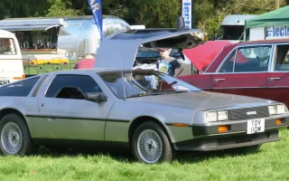 DeLorean DMC-12 z rocznika 1981 z jednym skrzydłem uniesionym w górę. Nielakierowana stal nierdzewna i drzwi otwierane jak u mewy — dokładnie ten obraz kazał twórcom „Powrotu do przyszłości" wybrać właśnie to auto.