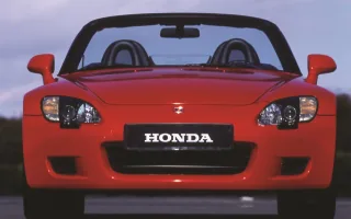 Czerwone AP1 w wieczornym świetle — twarz, którą Honda dała roadsterowi na swoje pięćdziesiąte urodziny. Wąskie reflektory, niska maska i ani jednego zbędnego gestu.