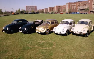 Pięć historycznych Volkswagenów Garbusów w rzędzie na trawie przed fabryką w Wolfsburgu — roczniki od 1938 do 1976.