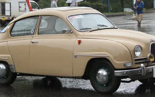 Beżowy Saab 96 z 1961 roku na placu podczas zlotu klasyków — ujęcie trzy czwarte z przodu.