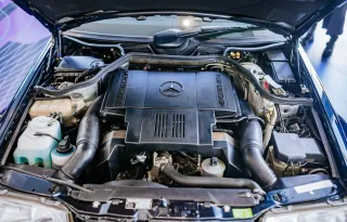 Komora silnika E500 z 1995 roku — pięciolitrowy V8 M119, którego od deski do deski budowało Porsche w Zuffenhausen. To najpotężniejsze i najrzadsze serce gamy 124, a nie typowy widok pod maską: większość typoszeregu jeździła na skromniejszych dieslach i r
