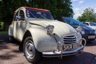 Kremowy Citroën 2CV z 1968 roku z bordowym dachem na zlocie klasyków — ujęcie trzy czwarte z przodu.