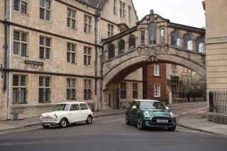 Klasyczny biały Morris Mini-Minor z 1959 roku obok zielonego MINI 60 Years Edition pod mostem na New College Lane w Oksfordzie.