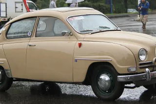 Beżowy Saab 96 z 1961 roku na placu podczas zlotu klasyków — ujęcie trzy czwarte z przodu.