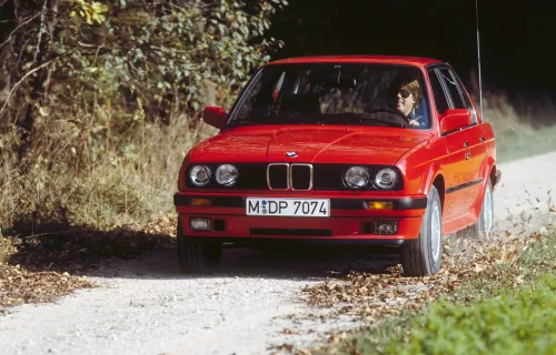 Czerwone E30 na szutrowej drodze, w materiałach prasowych BMW. Egzemplarz w takim stanie trafia dziś do ogłoszeń rzadko, a jego cena zaczyna się tam, gdzie inne się kończą.