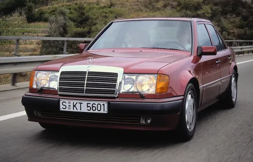 500E z 1990 roku, jeszcze przed liftingiem, w pełnym studyjnym ujęciu. Z daleka zwykły 124 — dopiero z bliska zdradzają go dyskretnie poszerzone błotniki i niżej osadzone nadwozie. To właśnie ten egzemplarz, składany ręcznie u Porsche w Zuffenhausen, zdef