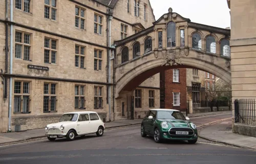 Klasyczny biały Morris Mini-Minor z 1959 roku obok zielonego MINI 60 Years Edition pod mostem na New College Lane w Oksfordzie.