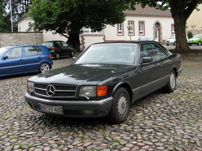 Napisy 500 SEC i AMG na jednej klapie to ślad przeróbki z Affalterbach, wykonywanej wtedy poza oficjalną gamą Mercedesa. Przy opuszczonych szybach widać bezsłupkowy bok — znak firmowy każdego coupé serii.