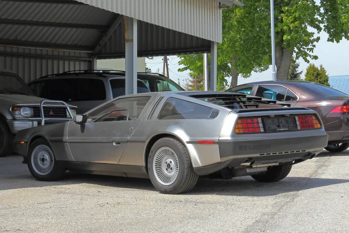 DeLorean DMC-12 w ujęciu trzy czwarte od tyłu. Kanciasta, klinowa sylwetka to podpis Giorgetta Giugiaro — tego samego, który narysował Volkswagena Golfa I i Lotusa Esprit. Auto z lat 80., które do dziś wygląda jak z filmu science fiction.