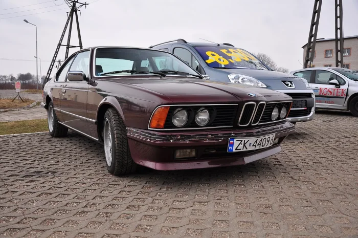 Bordowa Szóstka na polskim placu, obok auto z ceną wypisaną na szybie. Rekiny wciąż wypływają z krajowych komisów — coraz rzadziej i coraz drożej.