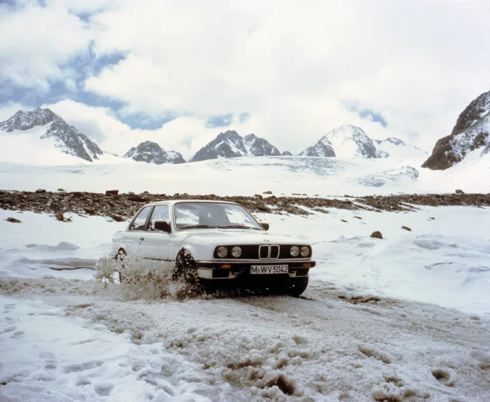 Archiwalne ujęcie prasowe BMW: E30 na łańcuchach, w śniegu po nadkola. Każdy zimowy sezon przejechany po solonej drodze dopisuje się do rachunku, który wystawi blacharz.