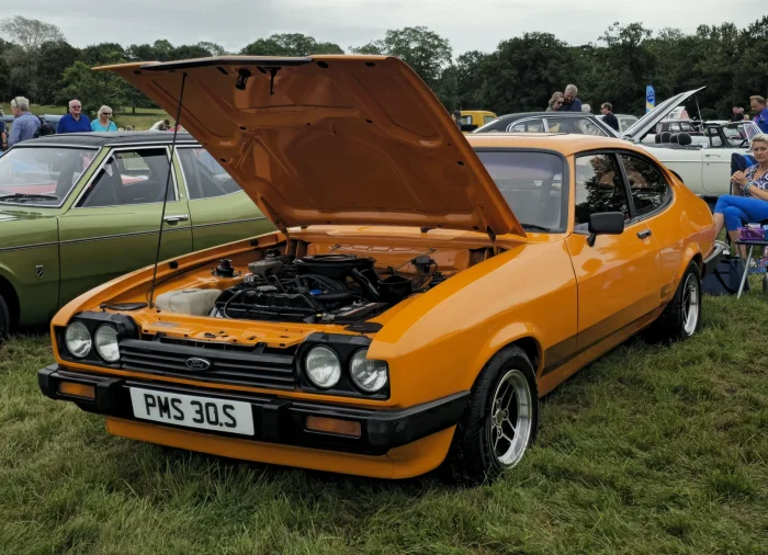 Ford Capri Mk3 3.0S — trzecia i ostatnia generacja z lat 1978–1986. Poczwórne prostokątne reflektory i czarna atrapa „Aeroflow” to jej znak rozpoznawczy; pod otwartą maską pracuje widlasta szóstka V6.
