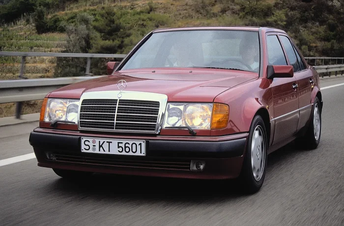 500E z 1990 roku, jeszcze przed liftingiem, w pełnym studyjnym ujęciu. Z daleka zwykły 124 — dopiero z bliska zdradzają go dyskretnie poszerzone błotniki i niżej osadzone nadwozie. To właśnie ten egzemplarz, składany ręcznie u Porsche w Zuffenhausen, zdef