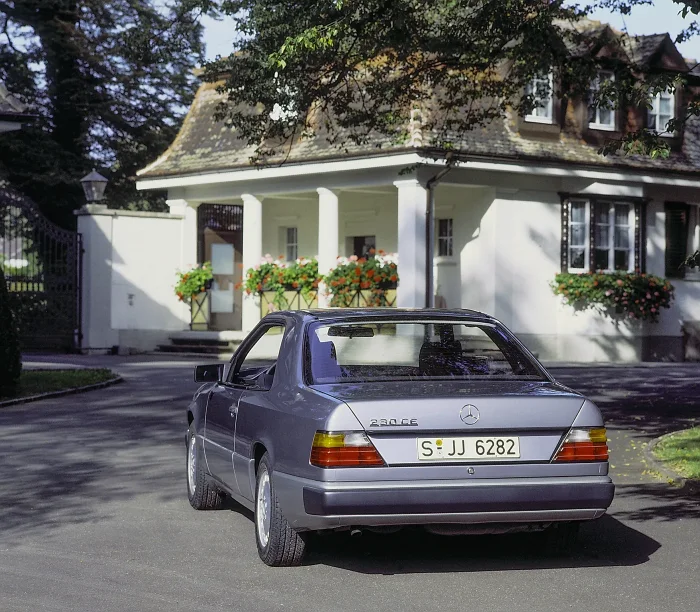 Tył coupé C124 z 1987 roku — linia dachu opadająca bez przerywającej ją belki słupka B. To w tylnej szybie coupé z czasem pojawia się charakterystyczne rozwarstwienie: mleczne smugi przy krawędziach. Wada kosmetyczna, ale kosztowna w naprawie — i pierwsza