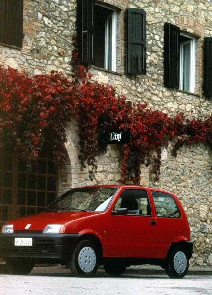 Czerwone Cinquecento w miejskim kadrze z materiałów prasowych. Odmiany ED, Young i Soleil miały jedno zadanie: uczynić nowe auto osiągalnym. *fot. Stellantis Heritage / archiwum Fiata*
