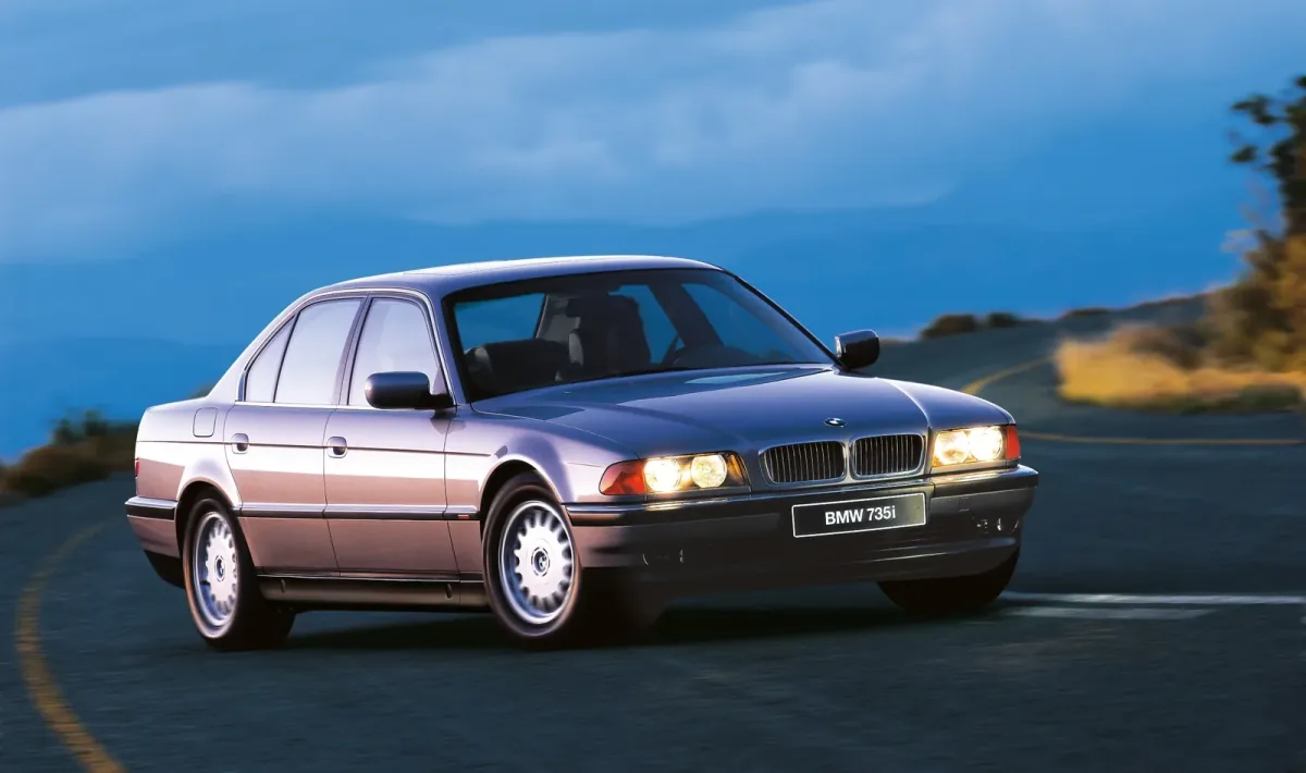 BMW 735i na górskiej drodze o zmierzchu. Ta powściągliwa bryła, ganiona w połowie lat dziewięćdziesiątych za brak prezencji, dziś czyta się jako klasa