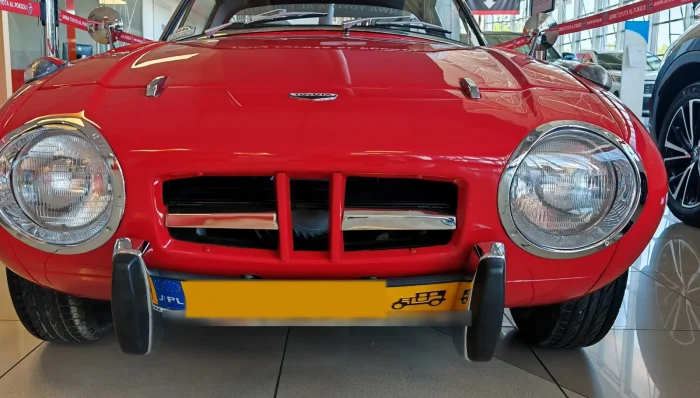Toyota Sports 800 z lat 60. z żółtą tablicą pojazdu zabytkowego w salonie w Krakowie.
