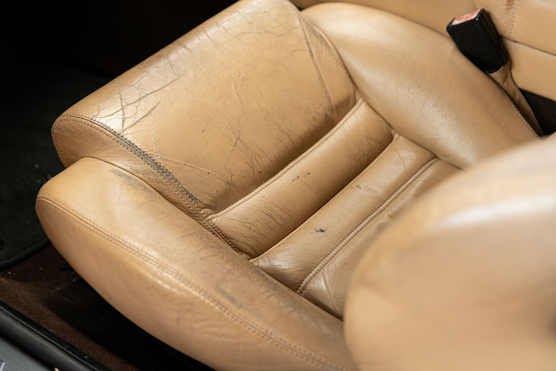 Podniszczony fotel samochodowy z tapicerką skórzaną